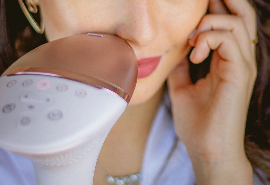 A woman using Philips Lumea BRI977 on her face for IPL hair removal at home